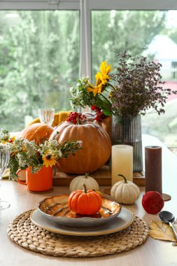 Yemek masasında balkabağı ve çiçeklerle sonbahar ayarı, yakın plan.