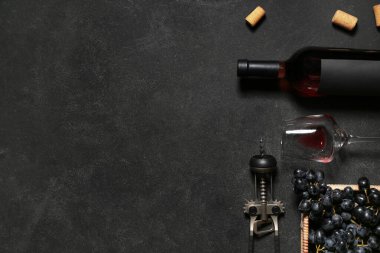 Siyah arka planda üzümlü bir bardak ve bir şişe nefis şarap.