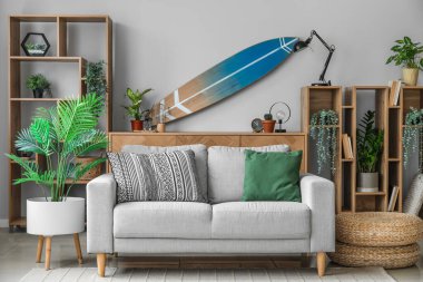 Sörf tahtası, raf ünitesi ve kanepesi olan bir oturma odası.