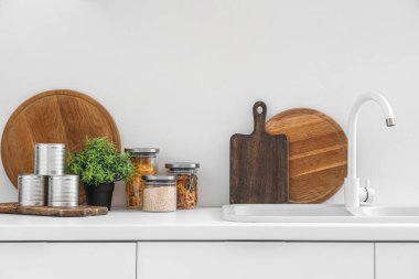 Modern mutfağın içinde lavabo ve çatal bıçaklarla dolu beyaz tezgahlar.