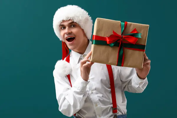 Shocked Santa Claus with gift box on dark green background