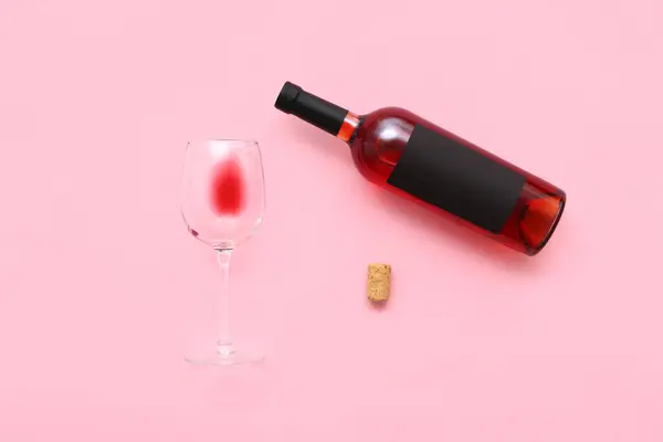 Glass and bottle of exquisite wine on pink background