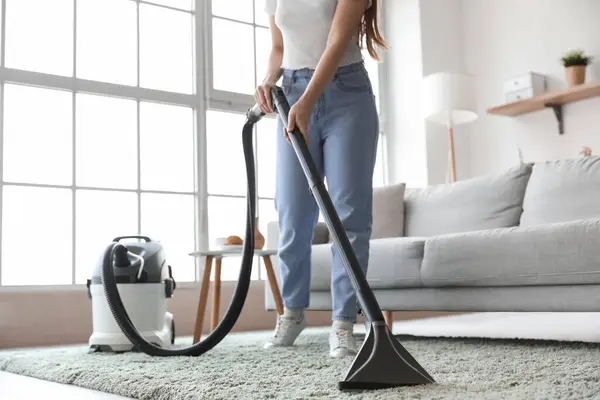 Young woman vacuuming carpet at home