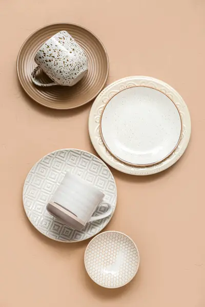 Set of stylish clean dinnerware on beige background