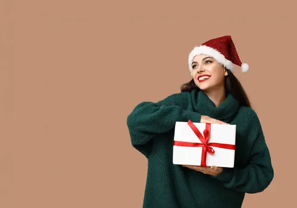 Mooie Jonge Vrouw Santa Hoed Met Kerstcadeau Bruine Achtergrond — Stockfoto