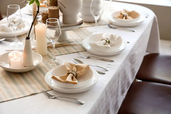Elegant table setting with candles, folded napkins and plates