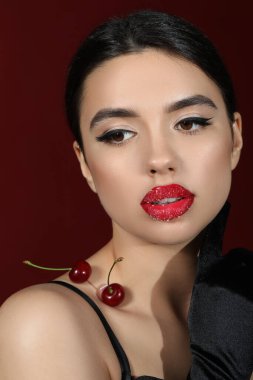 Tatlı dudaklı güzel bir kadın ve koyu arkaplanda kırmızı kirazlar, yakın plan
