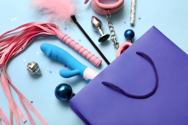 Seks oyuncakları ve mavi arka planda Noel dekoru olan bir alışveriş çantası.