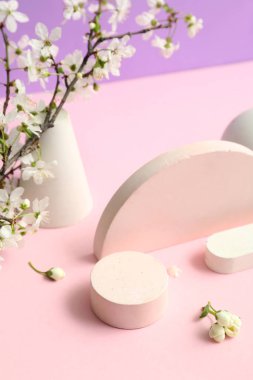 Eflatun arka planda dekoratif podyumlar ve çiçek açan şubeler