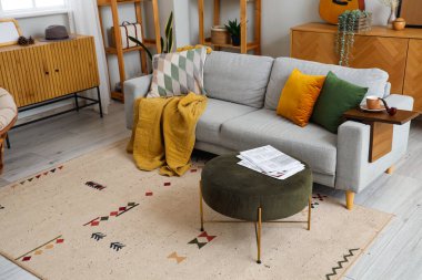 Gri kanepe, kanepe ve ahşap mobilyalarla modern oturma odasının içinde.