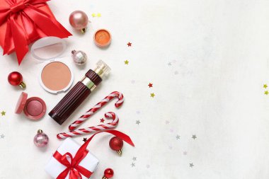 Parfümlü makyaj ürünleri ve beyaz grunge arka planda Noel dekoru.