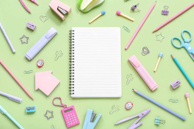 Yeşil arka planda farklı kırtasiye malzemesi içeren defter