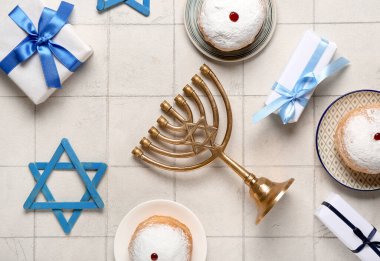 Menoralı Hannukah kompozisyonu, çörekler ve beyaz fayanslı masa üzerinde hediye kutusu.