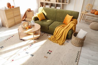 İçinde yeşil kanepe ve balkabağı olan oturma odasının içi.