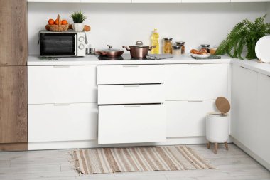 Modern mutfağın içinde şık halı, çöp kutusu ve beyaz tezgahlar var.