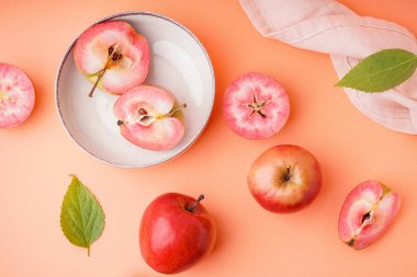 Tatlı pembe elma tabakları ve turuncu arka planda yapraklar.