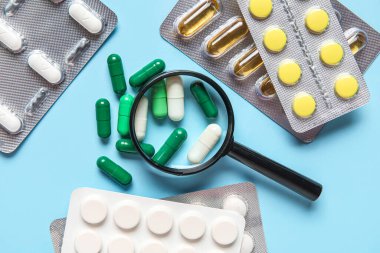 Mavi arka planda farklı haplar içeren büyüteç