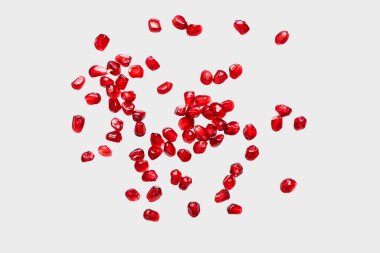 Gri arkaplanda taze nar tohumları uçuşuyor.