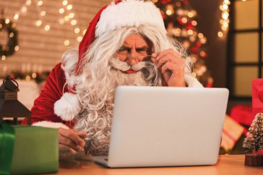Noel arifesinde evde dizüstü bilgisayarlı Noel Baba