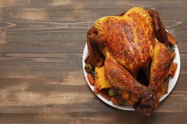 Ahşap zemin üzerinde Şükran Günü için lezzetli kızarmış hindi ve farklı sebzelerle dolu bir tabak.