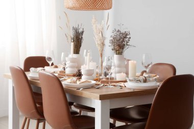 Kurumuş çiçekleri, yanan mumları ve kozalakları olan zarif bir masa.