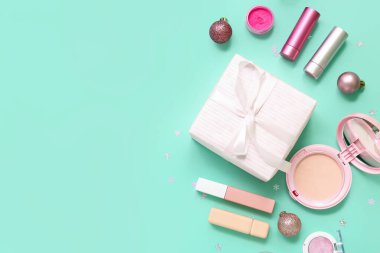 Makyaj ürünleri ve turkuaz arka planda Noel dekorundan yapılmış çerçeve