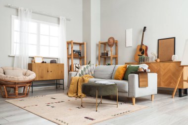 Gri kanepe, kanepe ve ahşap mobilyalarla modern oturma odasının içinde.