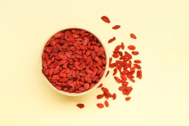 Sarı arka planda kırmızı kurutulmuş goji üzümlü kase.