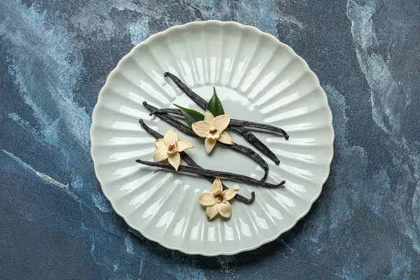 Aromatik vanilyalı tabaklar ve mavi arka planda çiçekler.