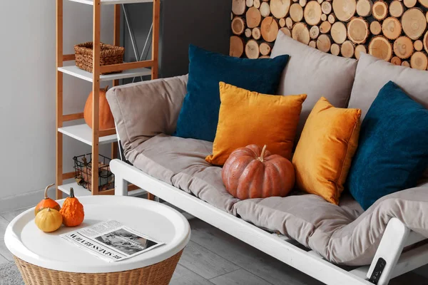Autumn interior of cozy living room with sofa, coffee table and pumpkins