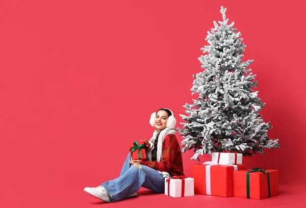 Mooie Jonge Vrouw Met Geschenkdozen Buurt Van Kerstboom Rode Achtergrond — Stockfoto