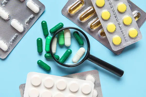 Mavi arka planda farklı haplar içeren büyüteç