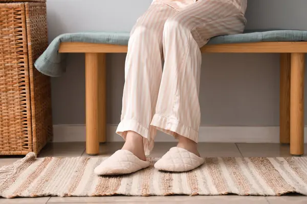 Evdeki bankta oturan yumuşak terlikli genç kadın.