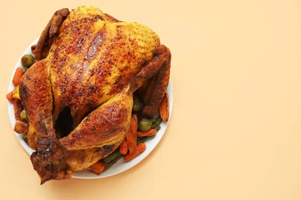 Bej arka planda, Şükran Günü için lezzetli kızarmış hindi ve farklı sebzeli tabak.