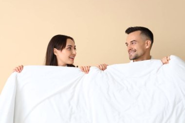 Bej arka planda yumuşak battaniyeli genç çift