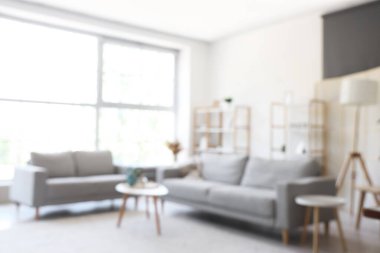 Gri kanepeler ve kahve masasıyla aydınlık oturma odasının bulanık görüntüsü