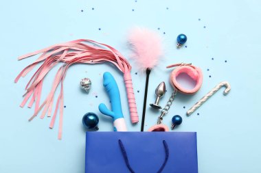 Seks oyuncakları ve mavi arka planda Noel dekoru olan bir alışveriş çantası.