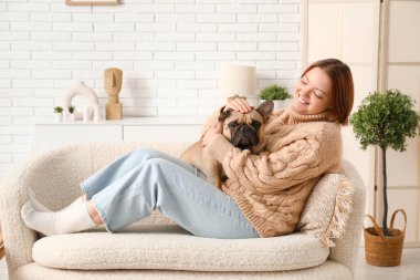Evdeki kanepede oturan sevimli köpekli genç kadın.