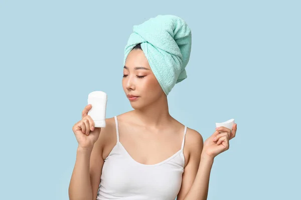 Young Asian woman with deodorant on blue background