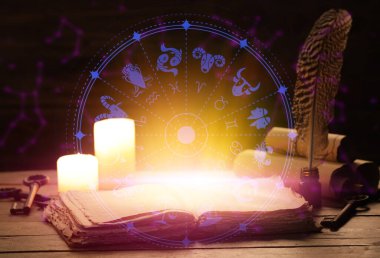 Açık kitap, mumlar ve astrolojik tabelalar karanlık arka plana karşı.