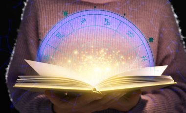 Koyu arkaplan üzerine astroloji kitabı okuyan kadın, yakın plan.