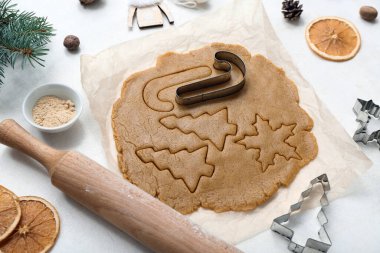 Hafif arka planda lezzetli Noel kurabiyeleri hazırlamak için ham hamur, baharat ve çatal bıçak