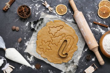 Koyu arkaplanda Noel kurabiyeleri hazırlamak için hamur, malzeme ve çatal bıçak içeren kompozisyon