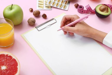 Boş panoya, kaleme ve sağlıklı yiyeceklere sahip kadın doktor, yakın plan.