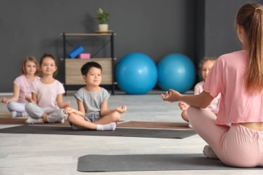 Beden eğitiminde meditasyon yapan bir grup küçük çocukla yoga eğitmeni.