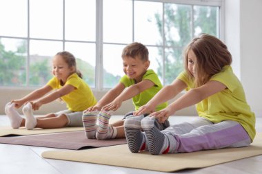 Beden dersinde yoga yapan bir grup çocuk.