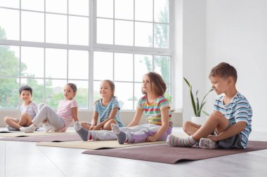 Beden dersinde yoga yapan bir grup çocuk.