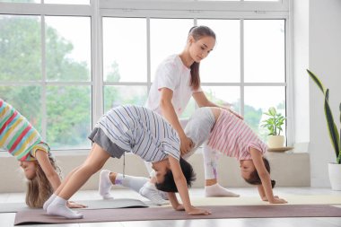 Beden eğitimi hocasıyla yoga yapan bir grup çocuk.