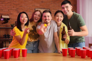Bir grup genç arkadaş partide bira pong oynuyorlar.