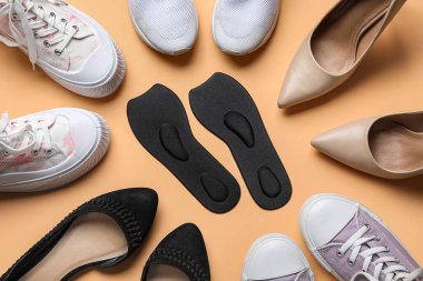Bej arka planda farklı spor ayakkabıları, ayakkabıları ve ortopedik tabanları olan kompozisyon